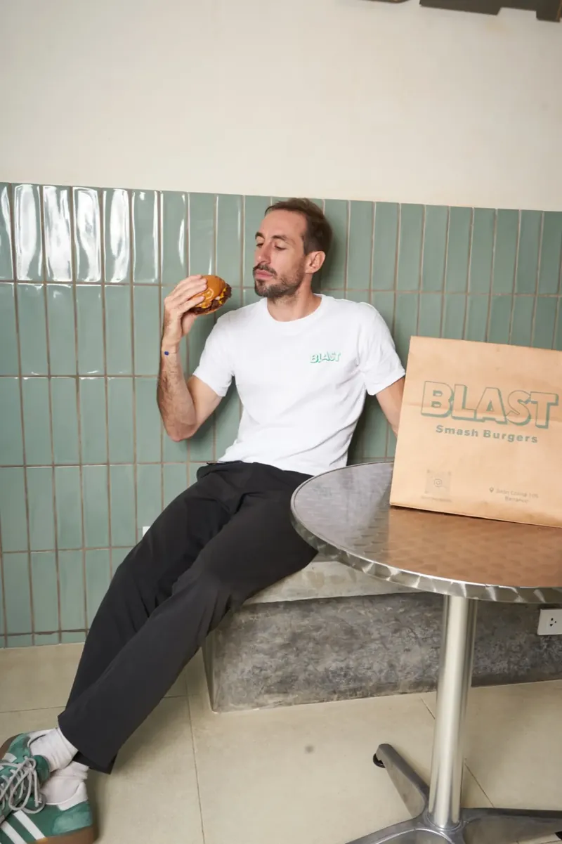 Un comensal disfruta una smash burger de Blast en el local