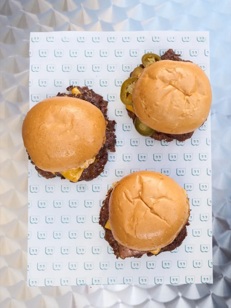 Tres smash burgers vistas desde arriba sobre papel de marca Blast